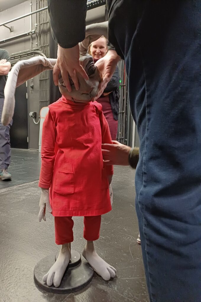 Das Bild zeigt einen Teilnehmer der Führung, der eine große Handpuppe in Form eines Hasen erkundet. Er hält die Puppe mit beiden Händen und tastet neugierig die weichen Ohren und den Kopf ab. Die Szene wirkt ruhig und konzentriert, als würde er sich ganz auf die Details der Puppe einlassen.